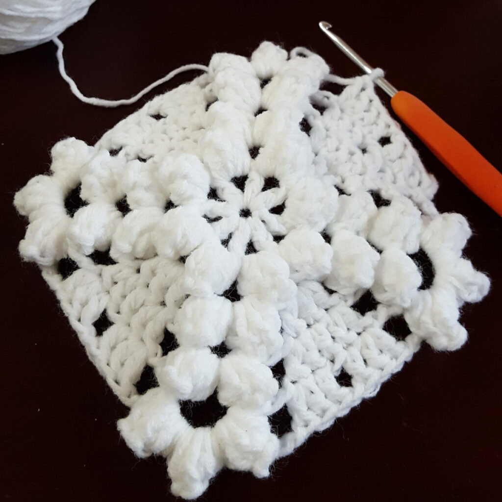 Crochet granny square with puff stitches.